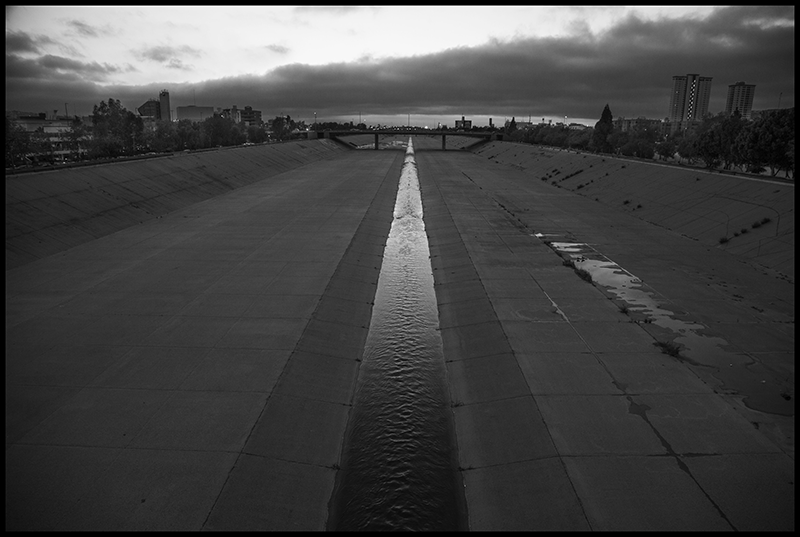 The Tijuana River runs down a concrete channel, with the Benito Juarez Park on the right. 